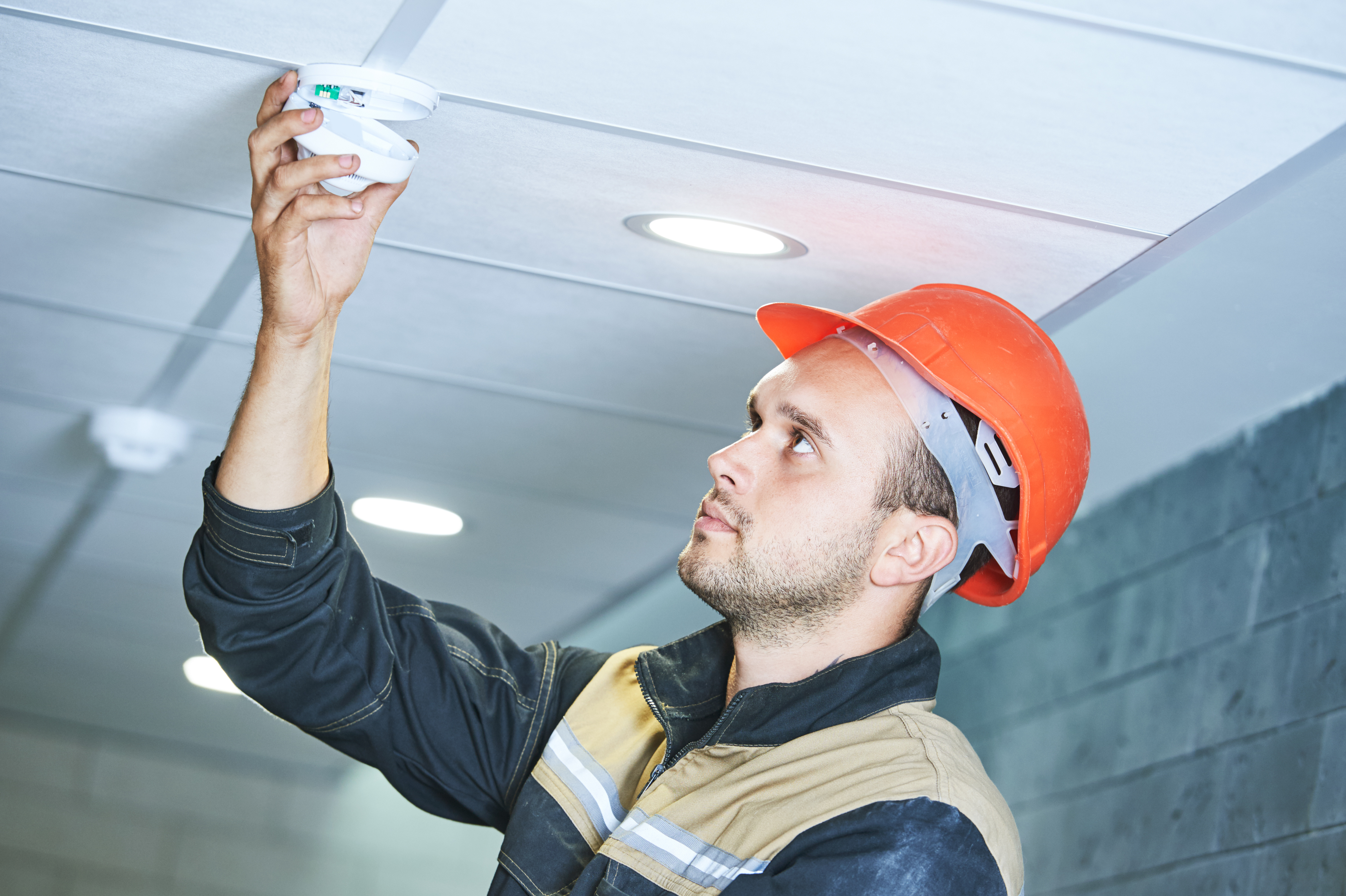 Worker Installing Smoke Detector On The Ceiling Grand Rapids Mi