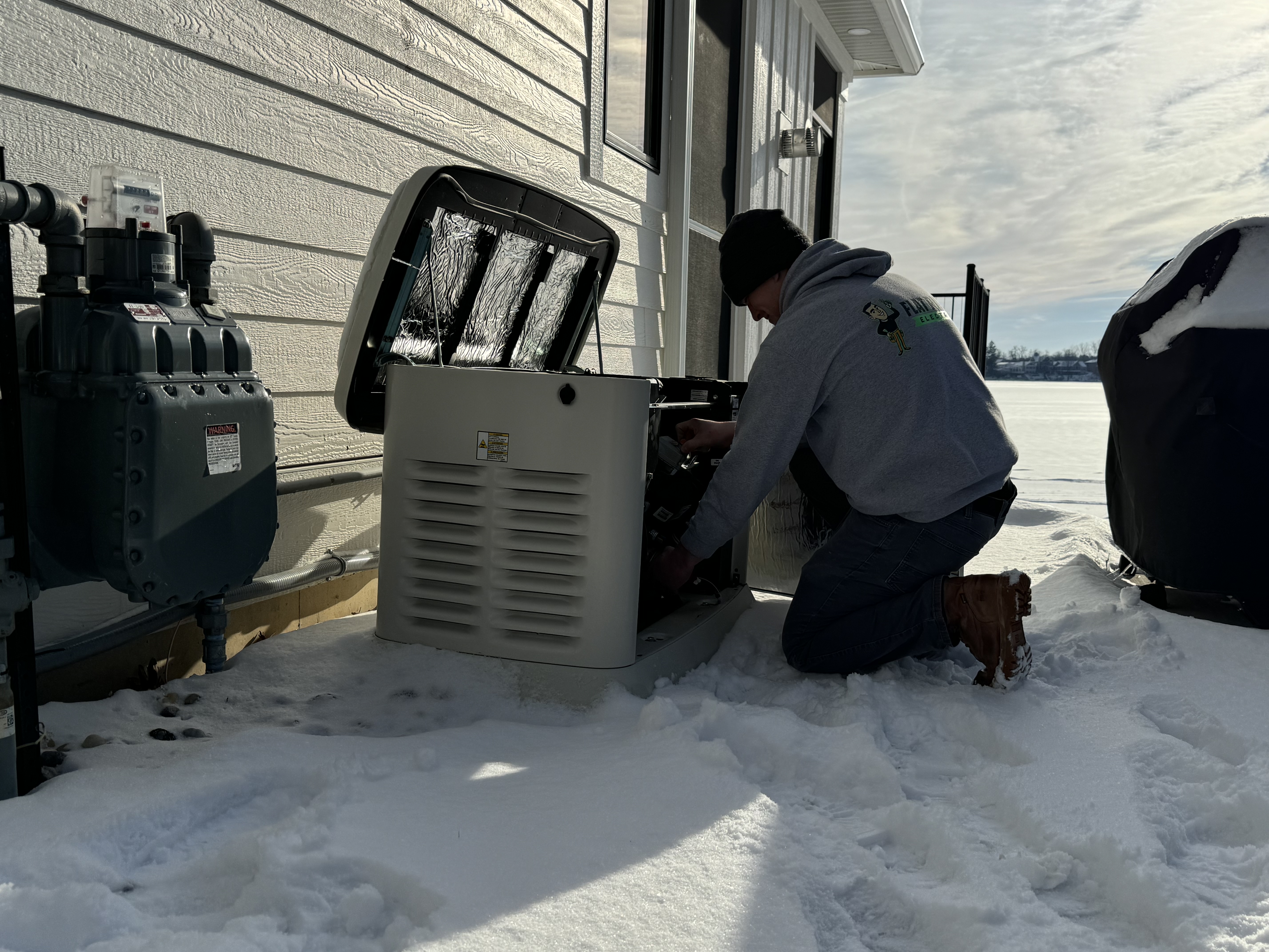 Electrician performing whole-home generator maintenance during winter in West Michigan
