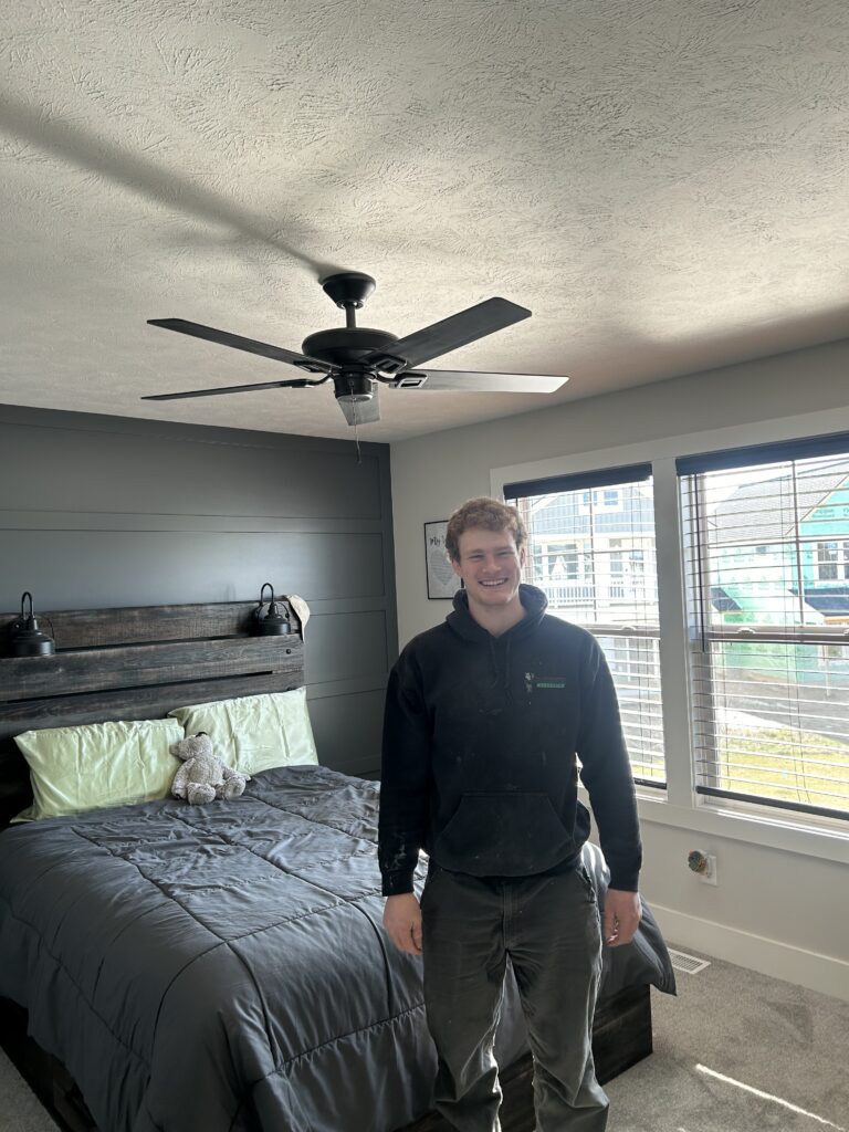 Flat River Electric technician beside a newly installed ceiling fan in a West Michigan bedroom.